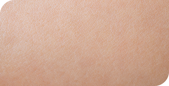 Macro-opname van een gezonde, lichte huid waarop de natuurlijke textuur en fijne lijntjes zichtbaar zijn.