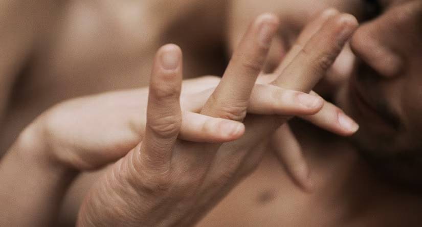 Intieme close-up van twee handen met ineengestrengelde vingers, wat een teder moment suggereert.