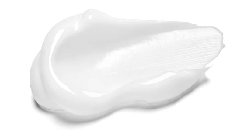 Een veeg van een dikke, witte crème op een witte achtergrond, waarin de zachte textuur zichtbaar is.