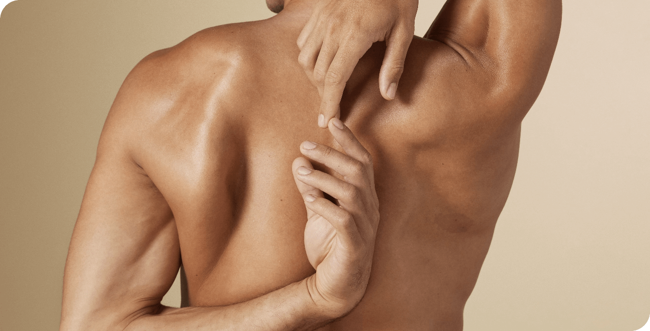 De gespierde rug van een man met een gebruinde huid die zijn armen strekt, waarbij zijn handen elkaar bijna raken achter zijn rug.